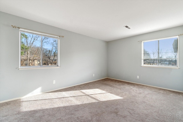 carpeted spare room with visible vents and baseboards