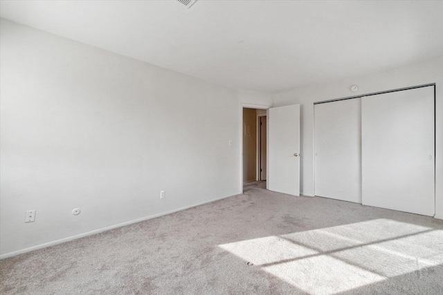 unfurnished bedroom with a closet and light colored carpet