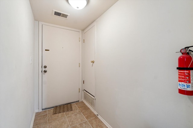 doorway with light tile patterned floors, baseboards, and visible vents