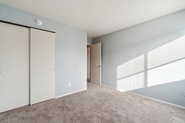 unfurnished bedroom featuring a closet, baseboards, and carpet