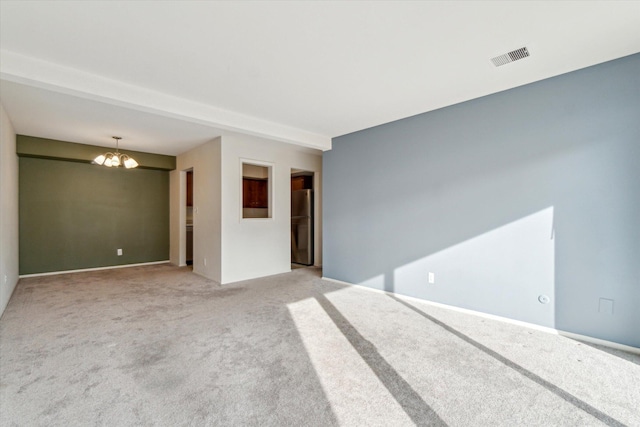 carpeted spare room with a chandelier and visible vents