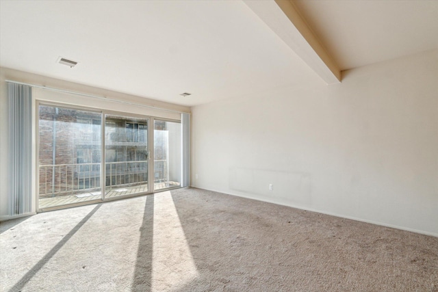 spare room with beamed ceiling, carpet, and visible vents