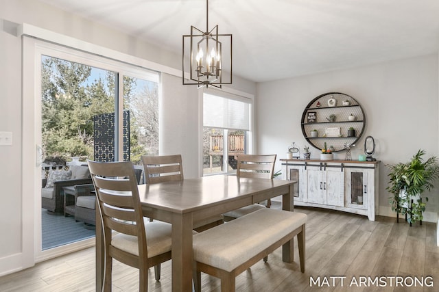 dining space with a chandelier, light wood-style flooring, and baseboards