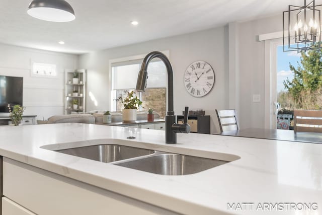 kitchen with light stone counters, recessed lighting, a sink, pendant lighting, and open floor plan