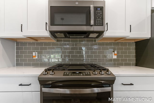 kitchen with light stone counters, stainless steel appliances, backsplash, and white cabinets