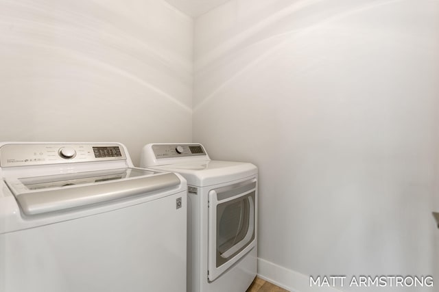 washroom with baseboards, separate washer and dryer, and laundry area