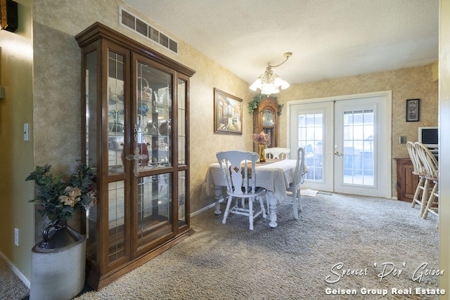 dining space featuring carpet, visible vents, an inviting chandelier, french doors, and a textured ceiling