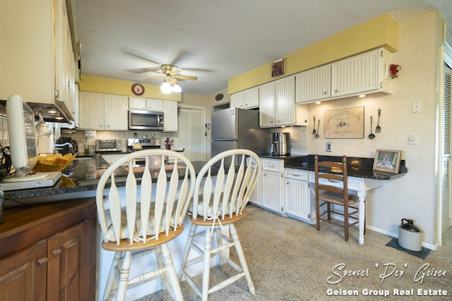 kitchen with a ceiling fan, dark countertops, tasteful backsplash, appliances with stainless steel finishes, and a peninsula