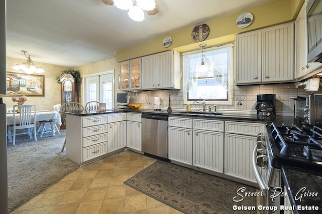 kitchen featuring a sink, dark countertops, stainless steel appliances, a peninsula, and light colored carpet