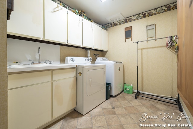 clothes washing area featuring a sink, attic access, cabinet space, and washing machine and clothes dryer