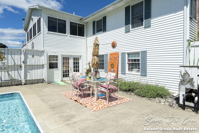 rear view of house with a patio area, an outdoor pool, and fence