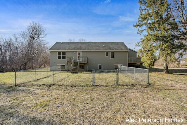 rear view of house featuring a deck, a gate, a lawn, and a fenced backyard