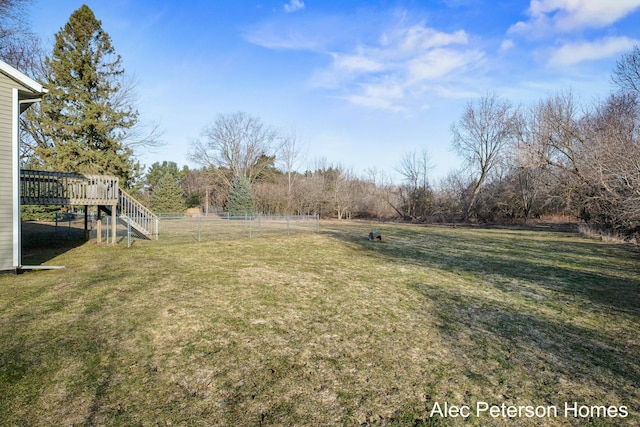 view of yard with a wooden deck, stairs, and fence