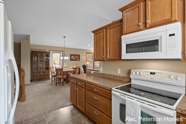 kitchen featuring white appliances, hanging light fixtures, dark colored carpet, dark tile patterned floors, and brown cabinets