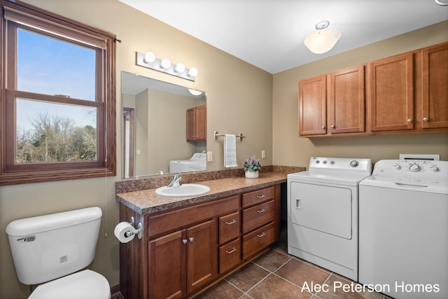 laundry area with washer and clothes dryer, laundry area, dark tile patterned flooring, and a sink