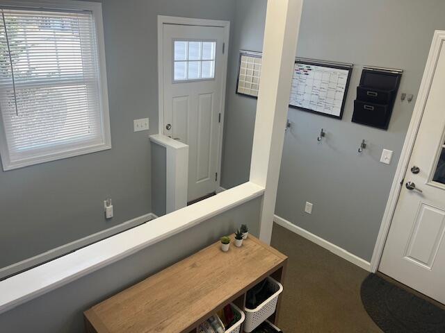 entryway featuring baseboards and dark carpet