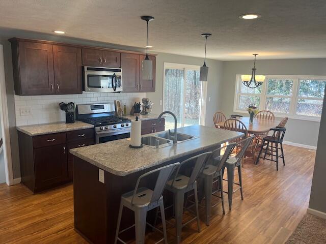 kitchen featuring stainless steel appliances, a healthy amount of sunlight, light wood-style flooring, and decorative backsplash