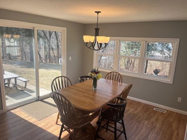 dining area with a notable chandelier, visible vents, baseboards, and wood finished floors