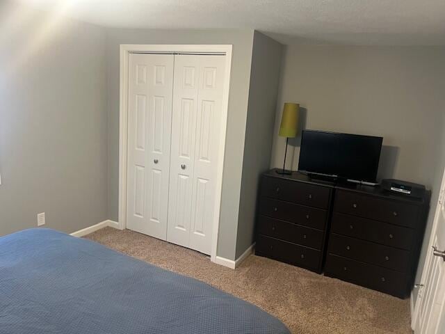 carpeted bedroom with a closet and baseboards