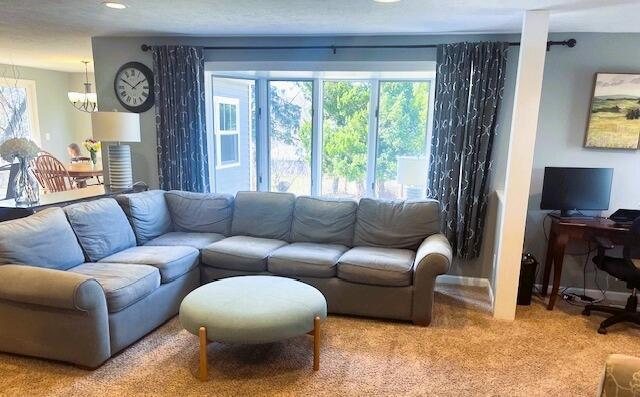 carpeted living area featuring an inviting chandelier