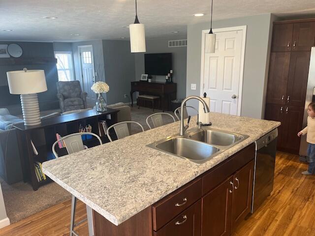 kitchen with visible vents, open floor plan, a breakfast bar, dishwashing machine, and a sink