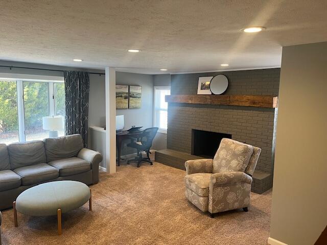 carpeted living room featuring recessed lighting, a brick fireplace, and a textured ceiling