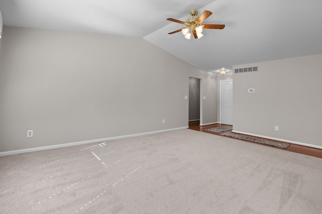 carpeted spare room with visible vents, lofted ceiling, baseboards, and ceiling fan