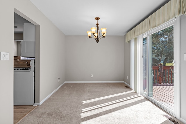 unfurnished dining area with visible vents, washer / clothes dryer, an inviting chandelier, baseboards, and light colored carpet