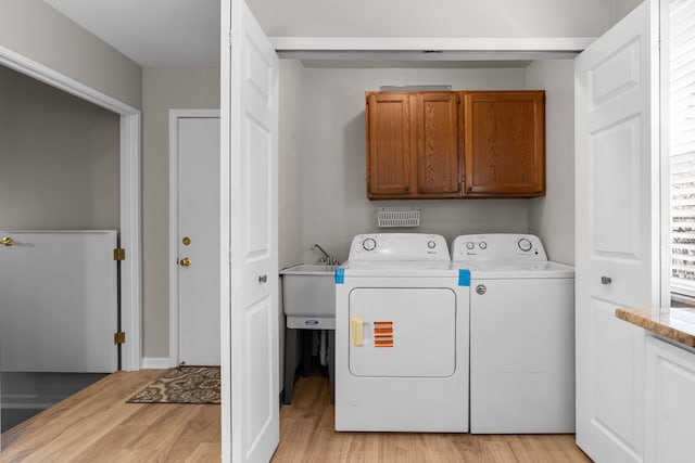 washroom featuring a sink, cabinet space, independent washer and dryer, and light wood-type flooring