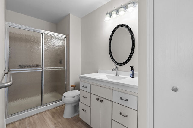 full bathroom with a shower stall, toilet, vanity, and wood finished floors