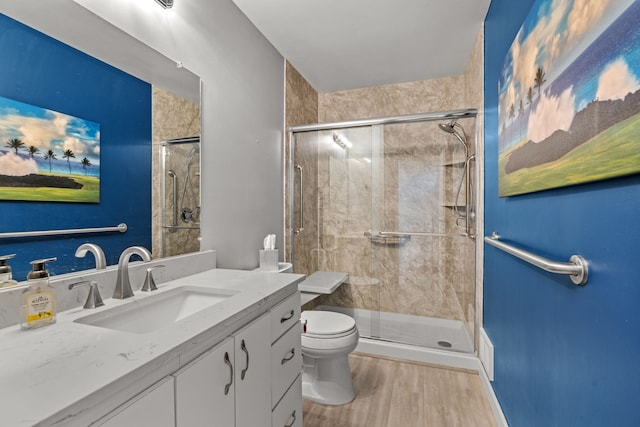 bathroom featuring vanity, toilet, wood finished floors, and a shower stall