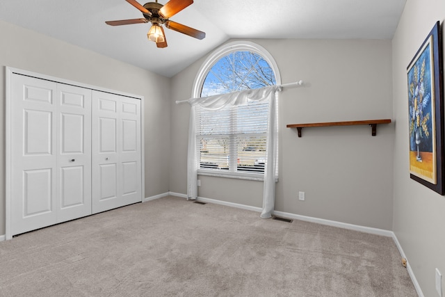 unfurnished bedroom featuring ceiling fan, baseboards, lofted ceiling, carpet floors, and a closet