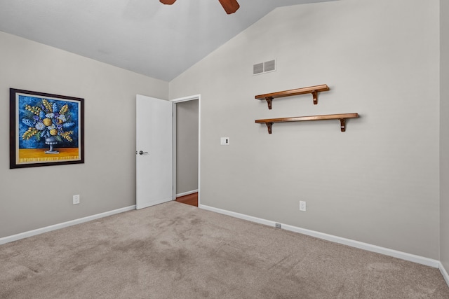 carpeted empty room featuring lofted ceiling, baseboards, visible vents, and ceiling fan