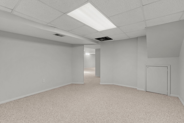 finished below grade area with a drop ceiling, visible vents, and carpet floors