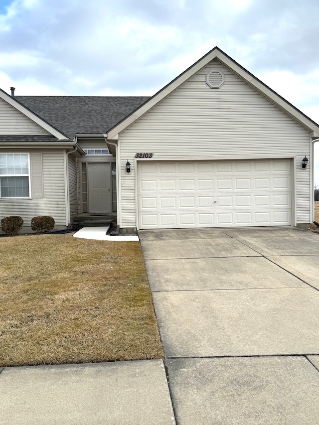 ranch-style home featuring concrete driveway, an attached garage, a front yard, and a shingled roof