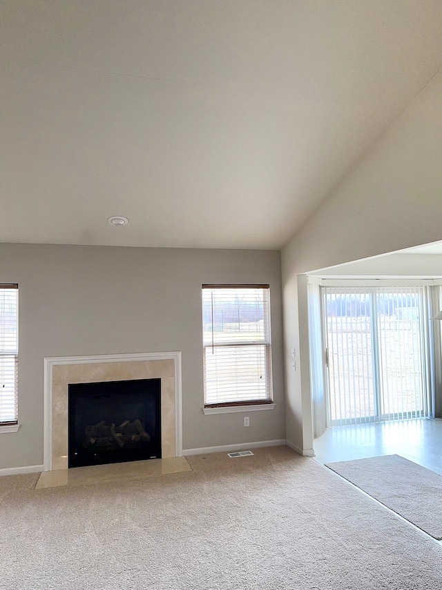 unfurnished living room featuring a healthy amount of sunlight, a high end fireplace, and carpet floors