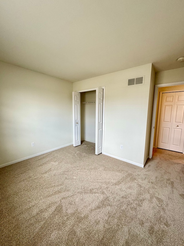 unfurnished bedroom featuring visible vents, carpet floors, baseboards, and a closet