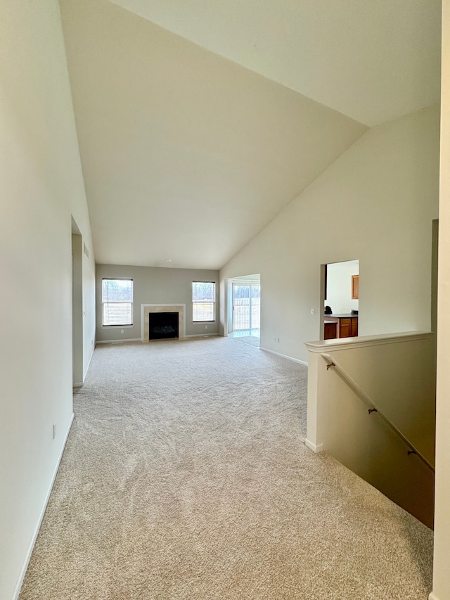 unfurnished living room with high vaulted ceiling, a fireplace, baseboards, and carpet