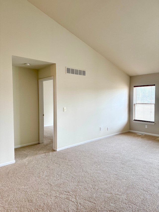 carpeted empty room featuring baseboards, visible vents, and high vaulted ceiling