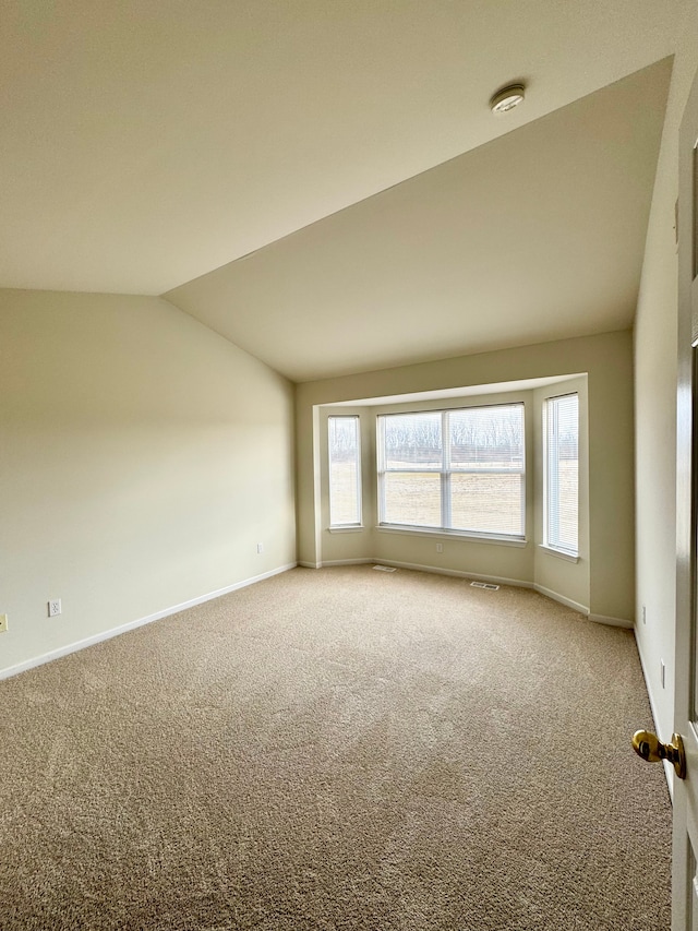 carpeted empty room featuring visible vents, baseboards, and vaulted ceiling