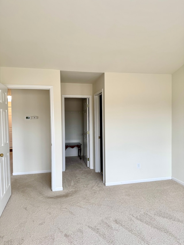 unfurnished bedroom with a spacious closet, carpet, baseboards, and a closet