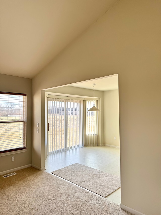 carpeted spare room featuring visible vents, baseboards, and vaulted ceiling