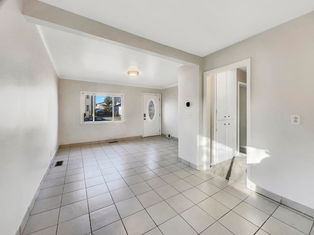 empty room with light tile patterned floors, visible vents, and baseboards