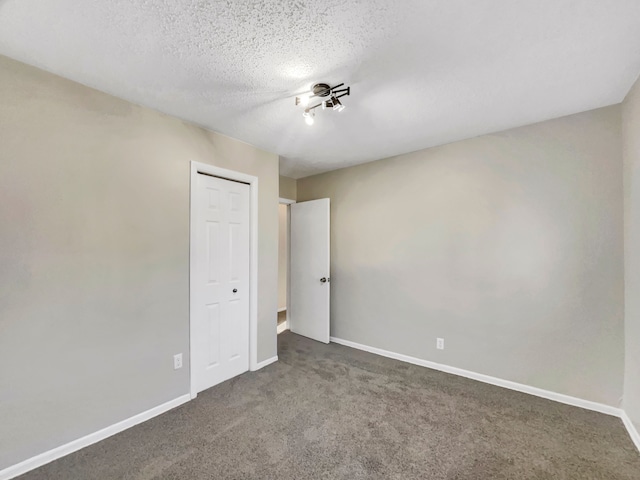 spare room with baseboards, carpet floors, and a textured ceiling