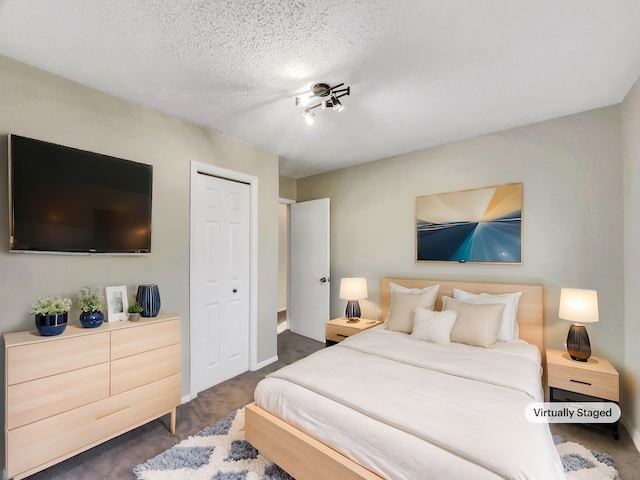 bedroom featuring carpet flooring, baseboards, a closet, and a textured ceiling