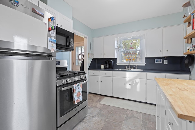 kitchen featuring a sink, wooden counters, appliances with stainless steel finishes, white cabinetry, and open shelves