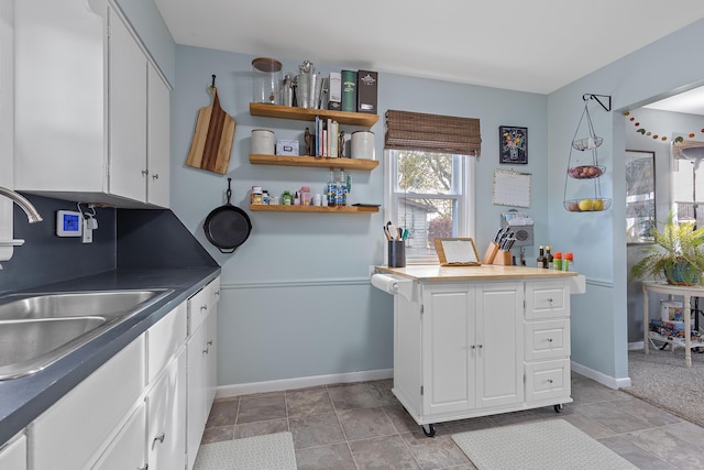 kitchen featuring a sink, baseboards, and white cabinetry