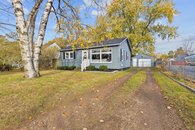 view of front of home with aphalt driveway, fence, an outdoor structure, a front yard, and a garage