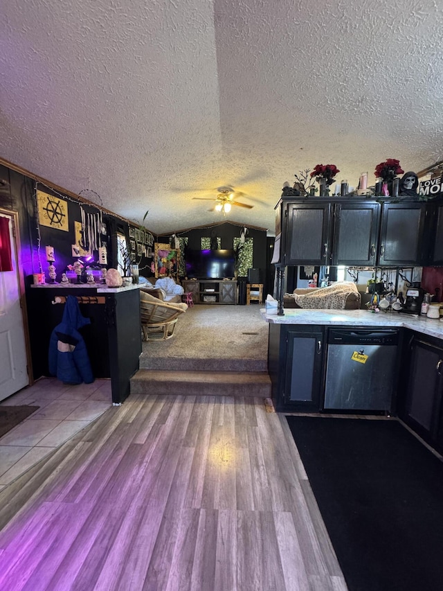 kitchen with wood finished floors, vaulted ceiling, light countertops, dishwasher, and dark cabinets