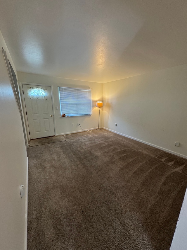 spare room with baseboards and carpet floors